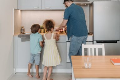 Father and children cooking together in a modern kitchen, enjoying family time.